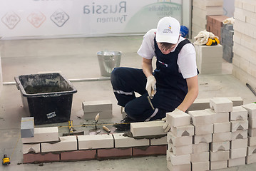 Image showing Young bricklayer performs a task of competition