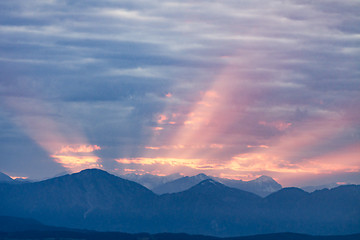 Image showing First rays rising sun over dark blue morning Alps mountains