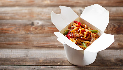 Image showing Noodles with pork and vegetables in take-out box on wooden table