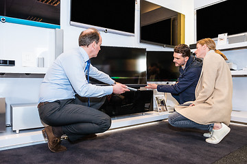 Image showing Assistant Showing Flat Screen Tv To Couple In Store