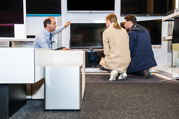 Image showing Salesman Showing Latest Flat Screen Tv To Couple