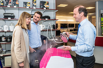 Image showing Salesman Showing Steam Iron To Couple In Hypermarket