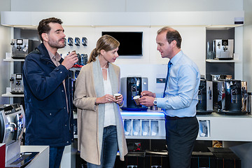 Image showing Salesman Showing Espresso Cups To Couple In Electronic Shop