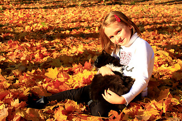 Image showing little girl plays with her cat in the autumn park