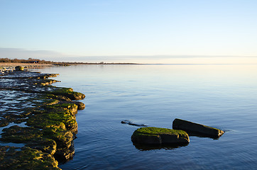 Image showing Flat rock coast with calm water 