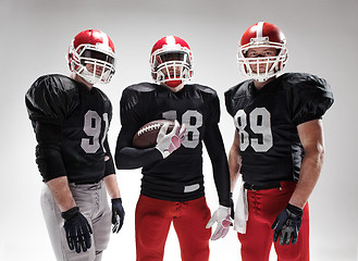 Image showing The three american football players posing with ball on white background