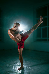 Image showing The young man kickboxing in blue smoke