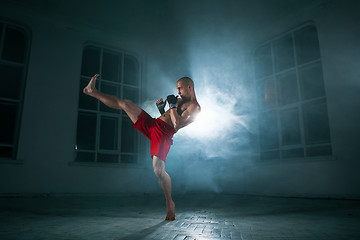 Image showing The young man kickboxing in blue smoke