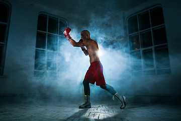 Image showing The young man kickboxing in blue smoke