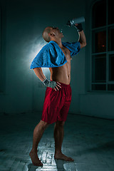 Image showing The young man kickboxing on black background