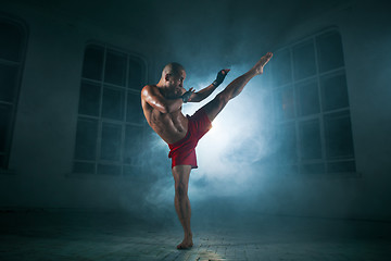 Image showing The young man kickboxing in blue smoke