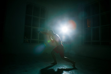 Image showing The young man kickboxing on black background