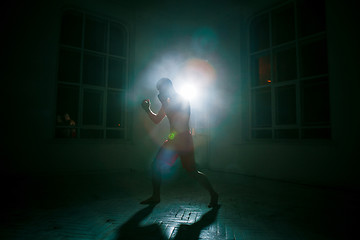 Image showing The young man kickboxing on black background