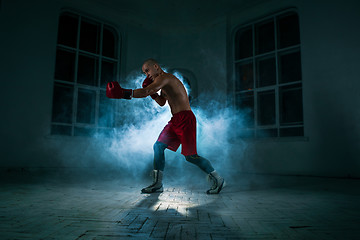 Image showing The young man kickboxing in blue smoke