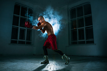 Image showing The young man kickboxing in blue smoke