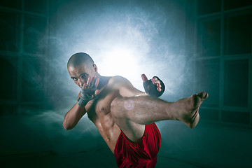 Image showing The young man kickboxing in blue smoke