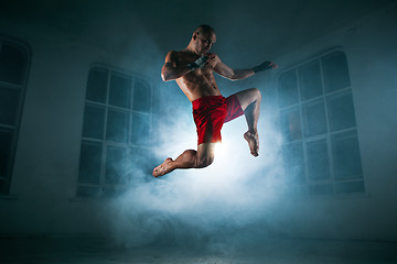 Image showing The young man kickboxing in blue smoke