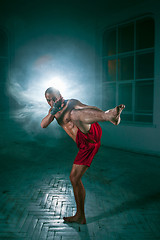 Image showing The young man kickboxing in blue smoke