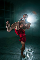 Image showing The young man kickboxing in blue smoke