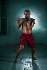 Image showing The young man kickboxing in blue smoke