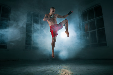 Image showing The young man kickboxing in blue smoke