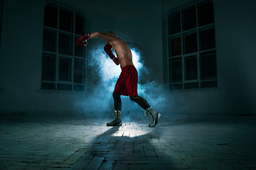 Image showing The young man kickboxing in blue smoke