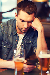 Image showing man with smartphone and beer texting at bar