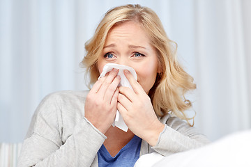 Image showing ill woman blowing nose to paper napkin