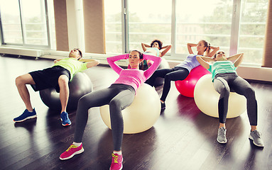 Image showing happy people flexing abdominal muscles on fitball