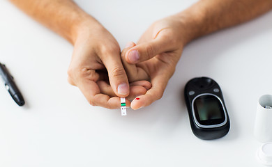 Image showing close up of man checking blood sugar by glucometer