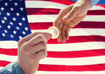 Image showing close up of male gay couple hands giving condom