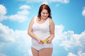 Image showing happy young plus size woman with measuring tape