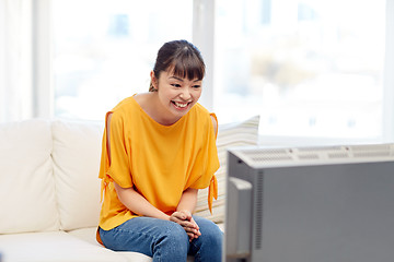 Image showing happy asian young woman watching tv at home