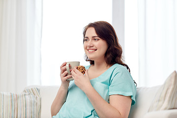 Image showing happy plus size woman with cup and cookie at home