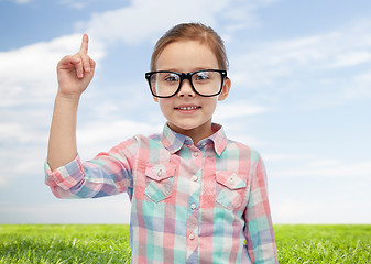 Image showing happy little girl in eyeglasses pointing finger up