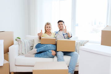 Image showing happy couple with boxes showing thumbs up at home