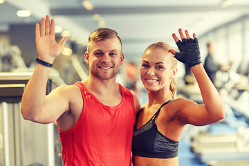 Image showing smiling man and woman waving hands in gym