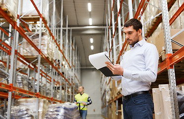 Image showing businessman writing to clipboard at warehouse