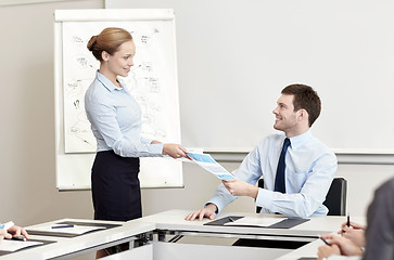 Image showing smiling woman giving papers to man in office