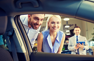 Image showing happy couple with car dealer in auto show or salon