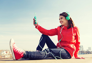 Image showing happy young woman with smartphone and headphones