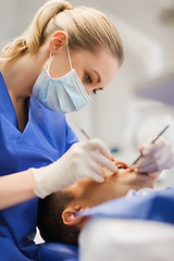 Image showing female dentist checking up male patient teeth