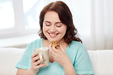 Image showing happy plus size woman with cup and cookie at home