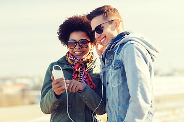 Image showing smiling couple with smartphone and earphones