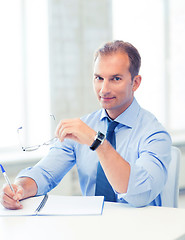 Image showing businessman with spectacles writing in notebook