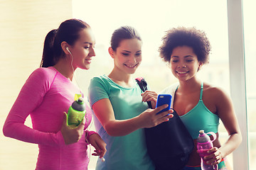 Image showing happy women with bottles and smartphone in gym