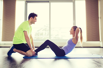 Image showing woman with personal trainer doing sit ups in gym