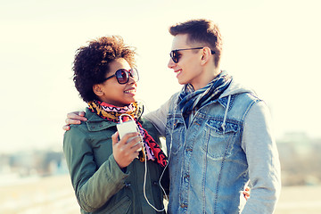 Image showing smiling couple with smartphone and earphones