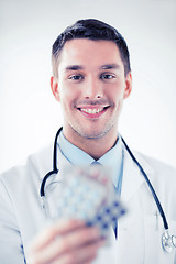 Image showing young male doctor with packs of pills