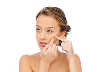 Image showing young woman squeezing pimple on her face